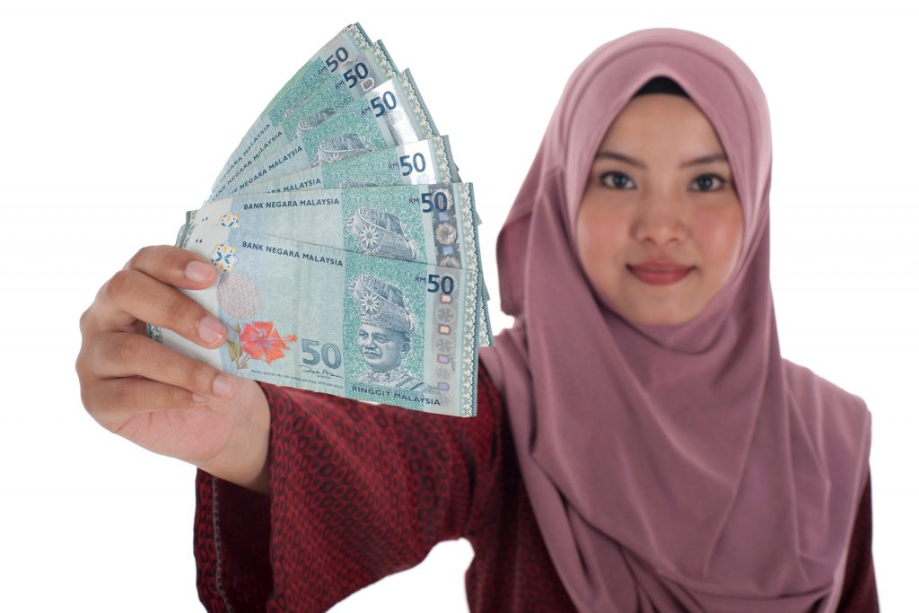 Smiling muslim woman holding a bunch of Malaysian Ringgit